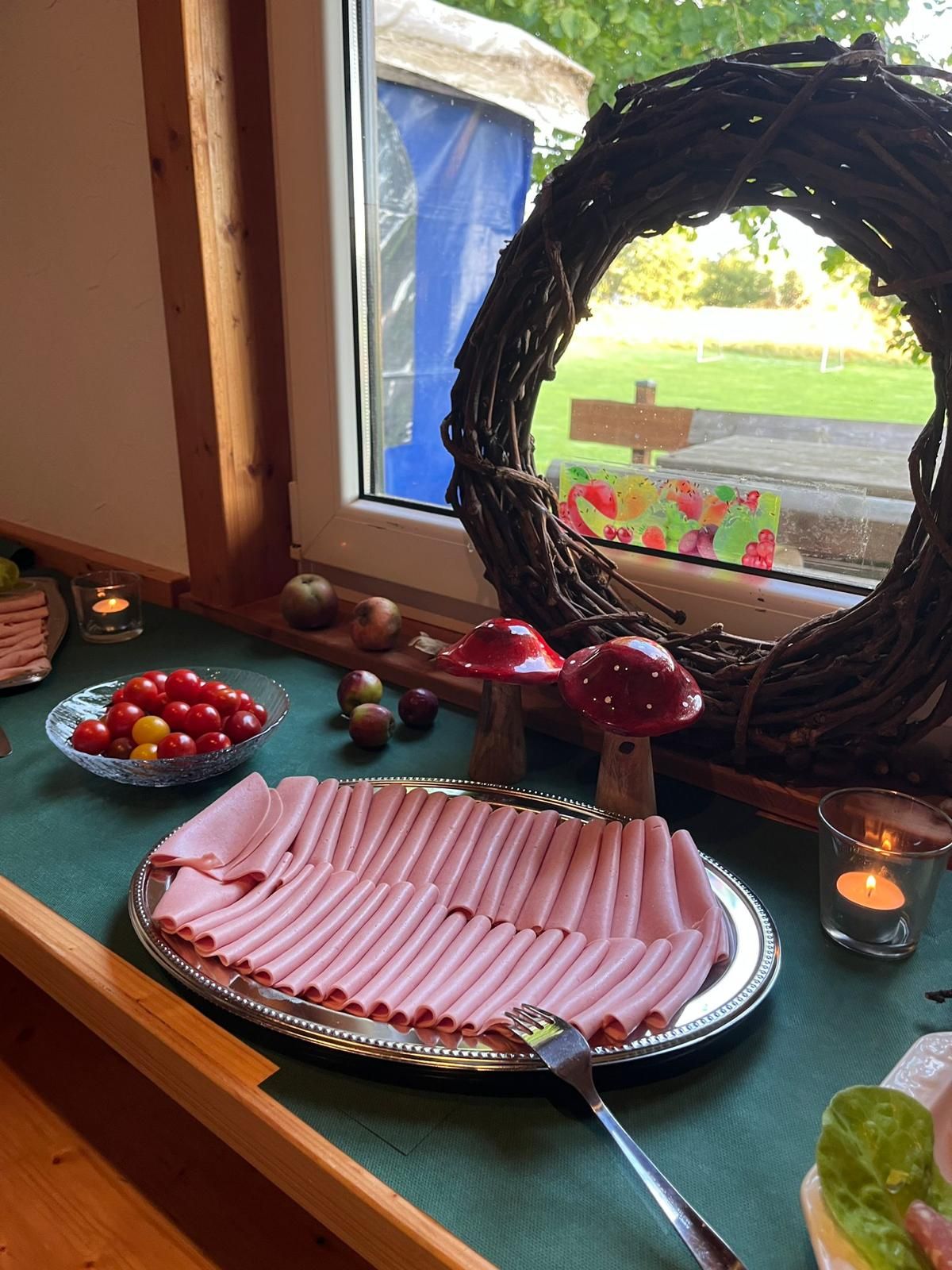 Wurstplatte mit Herbstdeko, Weidenkranz und Fliegenpilzen am Fenster