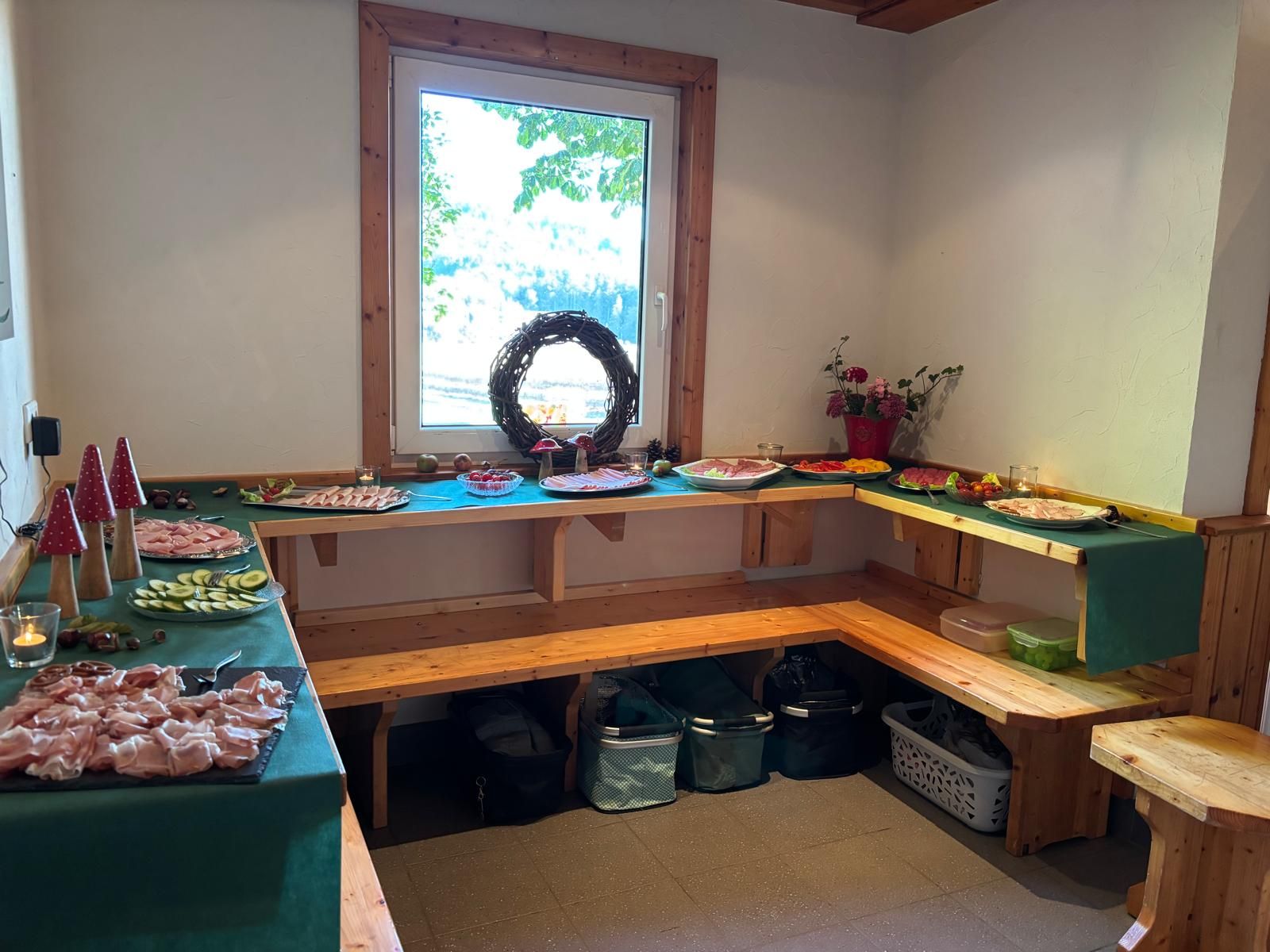 Innenraum mit umlaufender Holzbank und festlich gedecktem Buffet am Fenster