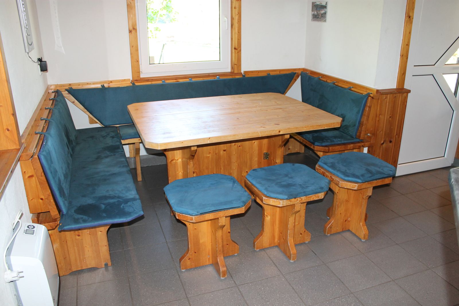 Multifunktionale Sitzecke mit Holztisch, blauen Polstern und Hockern im Innenraum