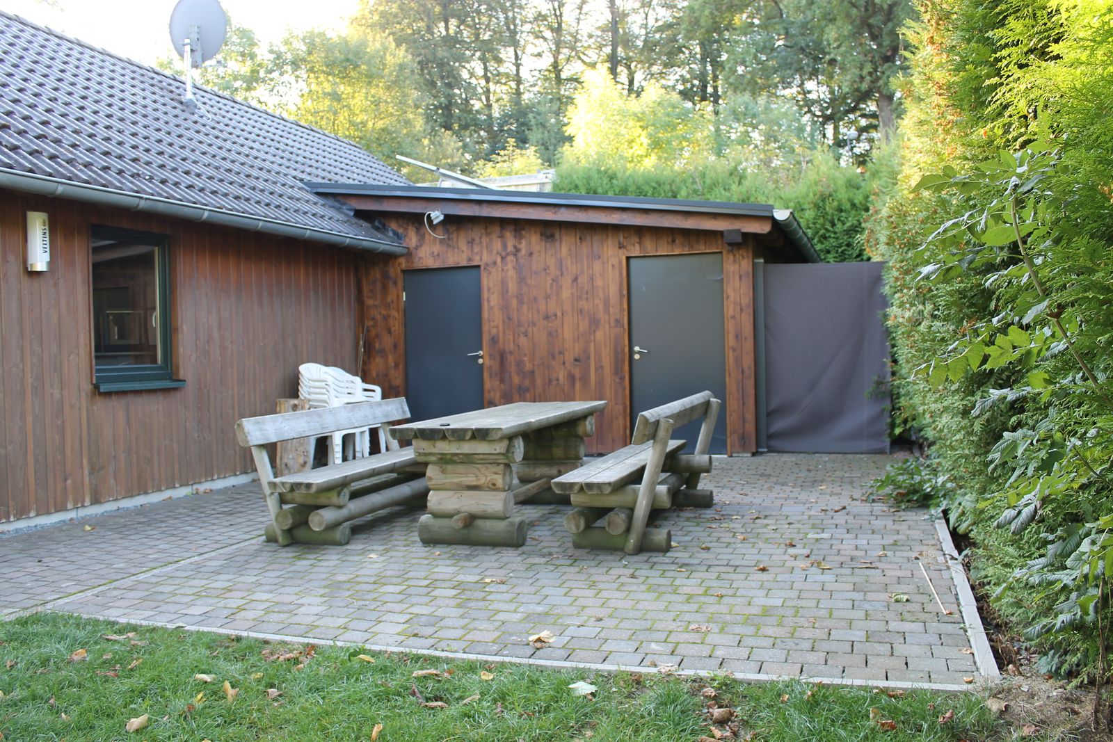 Gepflasterter Sitzplatz hinter der Hütte mit Steintisch und Bänken