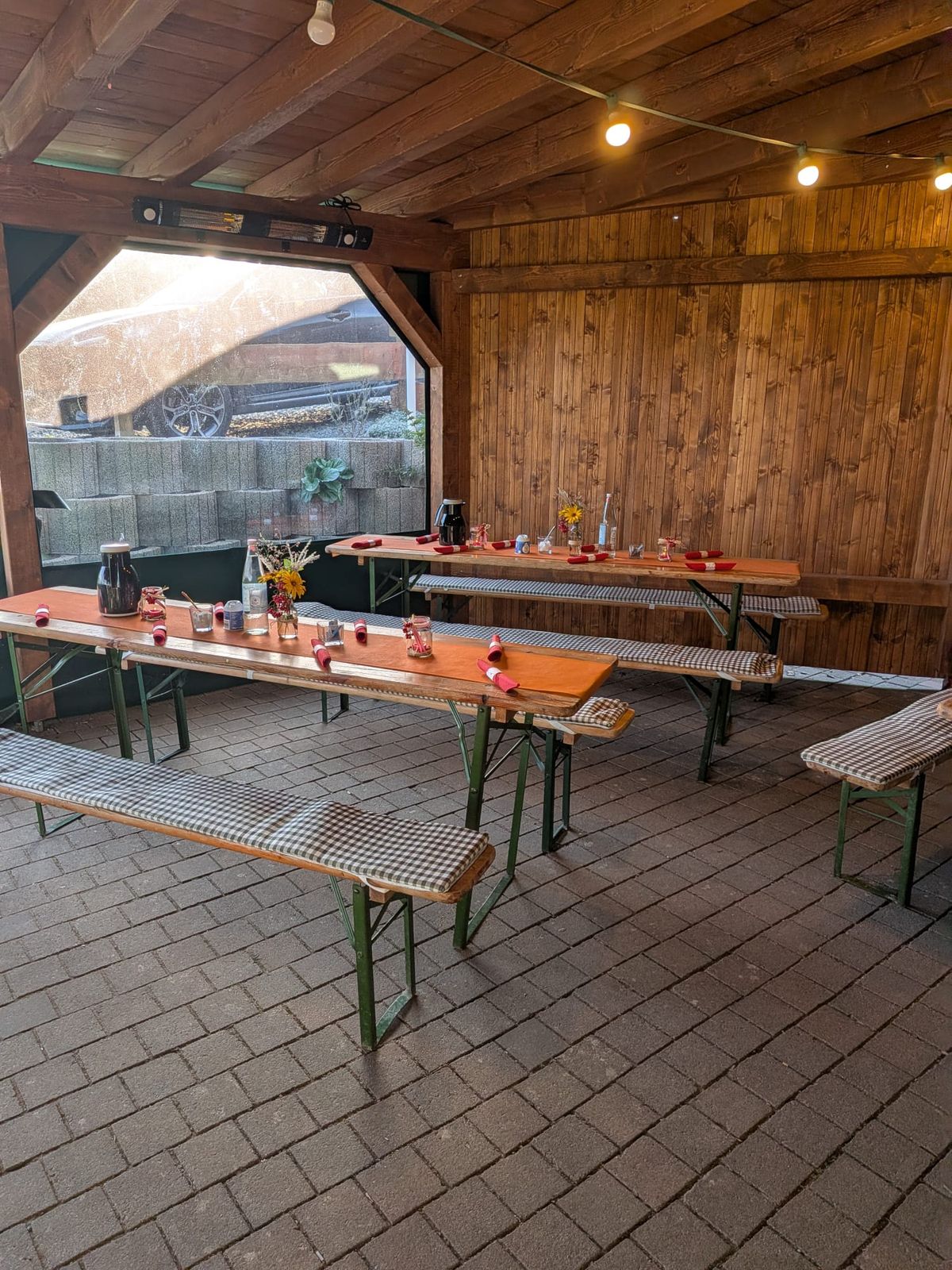 Überdachter Unterstand mit Bierzeltgarnituren, Sitzkissen und Lichterkette